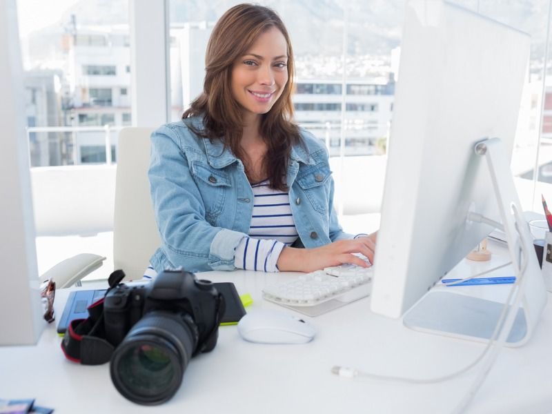 Woman smiling at a desk with camera - 13 Best Real Estate Video Tips - Image