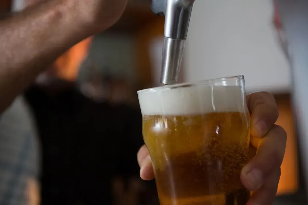 Brewer filling beer in beer glass from beer pump in bar - Image