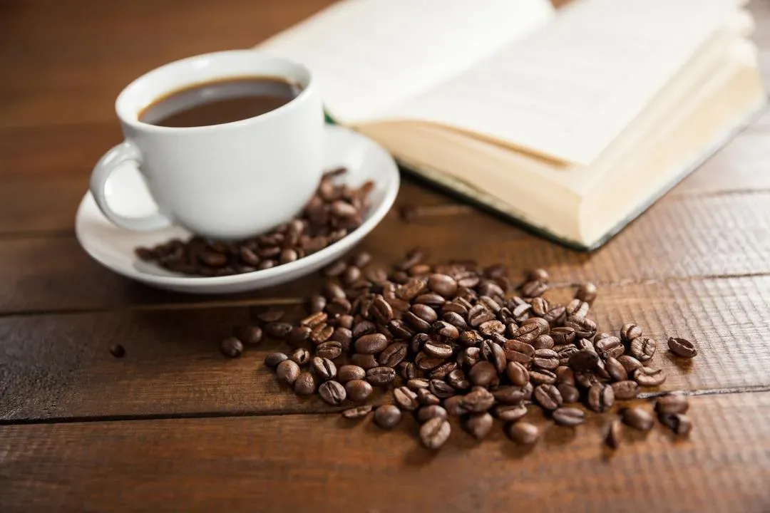Cup of coffee with coffee beans and book