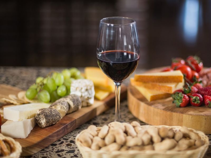 A glass of red wine and snacks - How to throw a wine and cheese party - Image