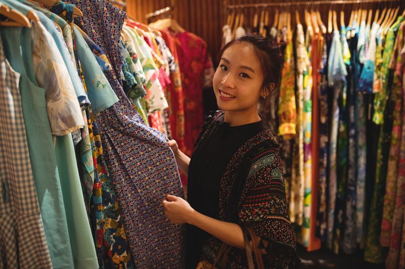 Asian girl in a clothing store - Choose clothes according to the party theme - Image