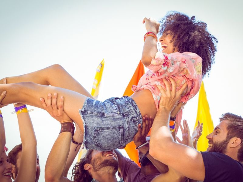 Excited woman crowd surfing at music festival - A festival birthday party idea - Image
