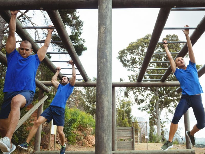 Fit people climbing monkey bars during an obstacle course - Flexibility of an obstacle-course-themed birthday party - Image