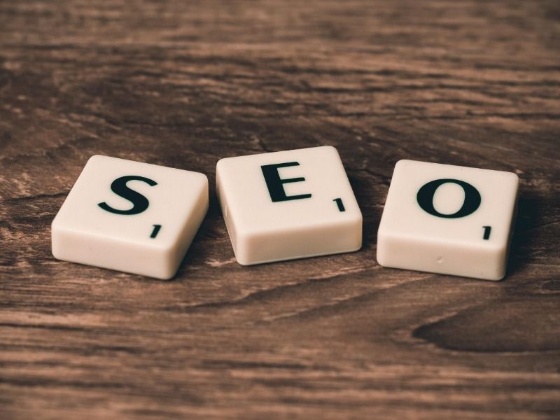The word SEO is made from Scrabble tiles on a brown wooden surface - Importance of SEO - Image