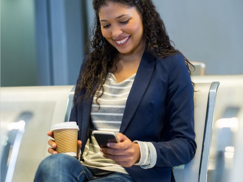 Female commuter with coffee cup using mobile phone in waiting area - How to establish emotional connections with your target audience - Image
