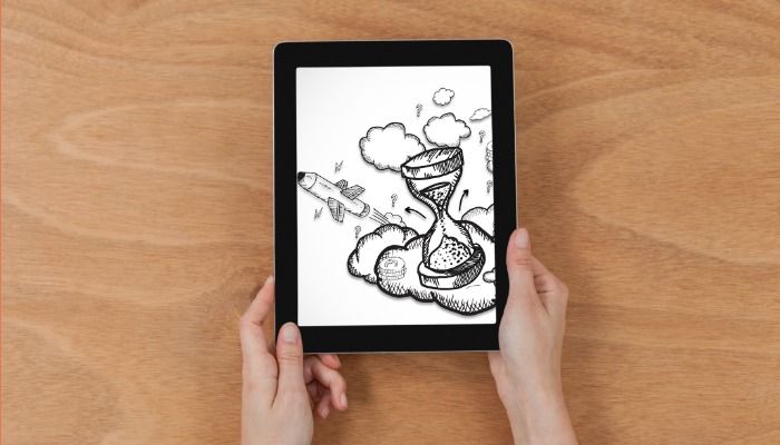 Person holding tablet with illustration on screen against a wood background - Top 50 free high-quality design resources for designers and entrepreneurs - Image