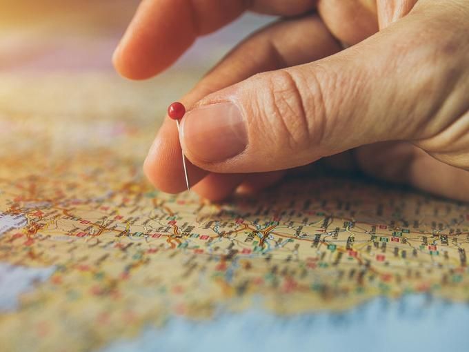 A person marks a place on the map with a red sewing pin - 80 Creative and inspiring engagement party ideas - Image