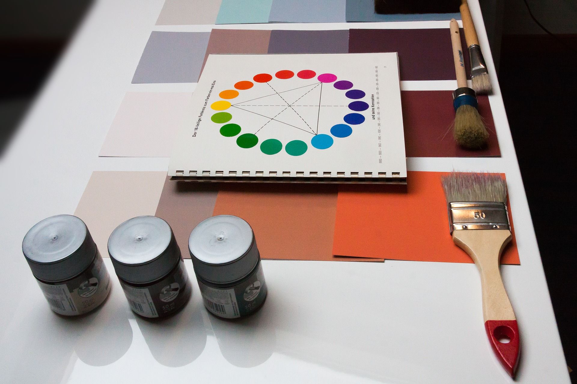 Color wheel, paints, and brushes lie on the table - How to effectively use visual communication in graphic design and why you should learn it now - Image