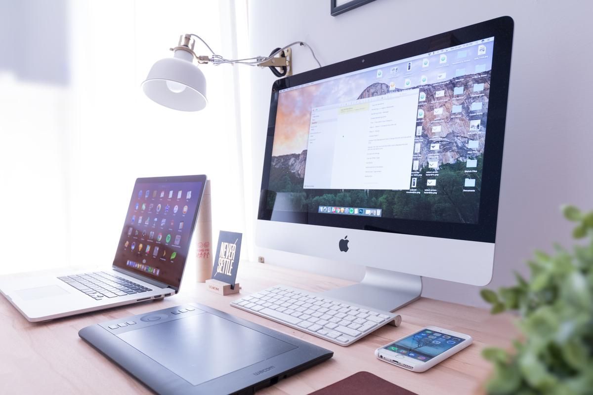 Image of a tabletop with a laptop, drawing tablet, Apple iMac, smartphone and plant - How to get more views on YouTube: The ultimate guide - Image