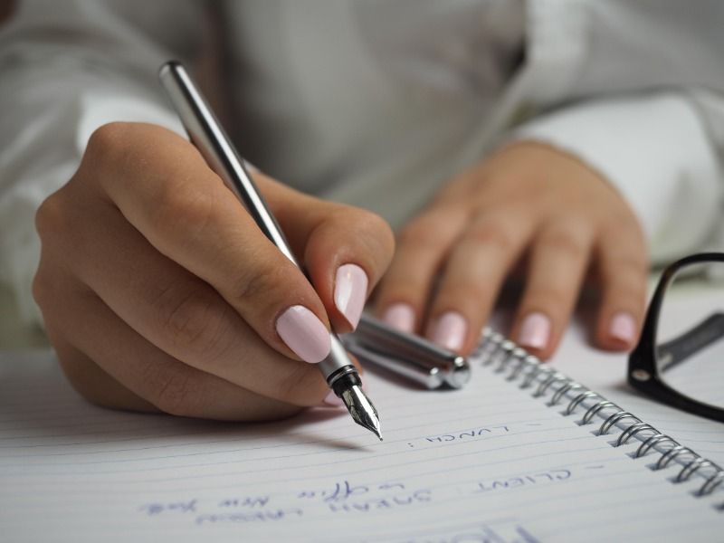 femme aux ongles peints écrivant dans un cahier - Comment créer un vlog - Image