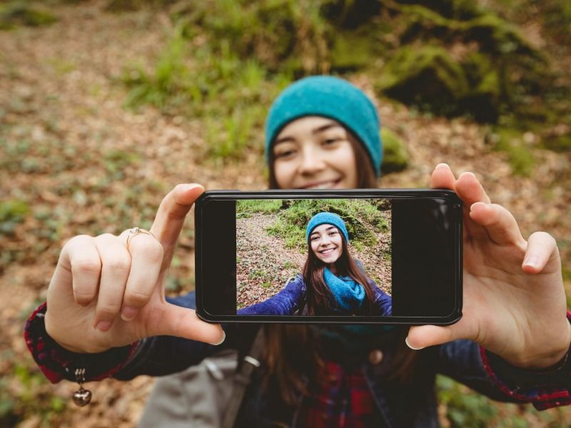 femme portant un chapeau prenant un selfie dans une forêt - Comment créer un vlog - Image