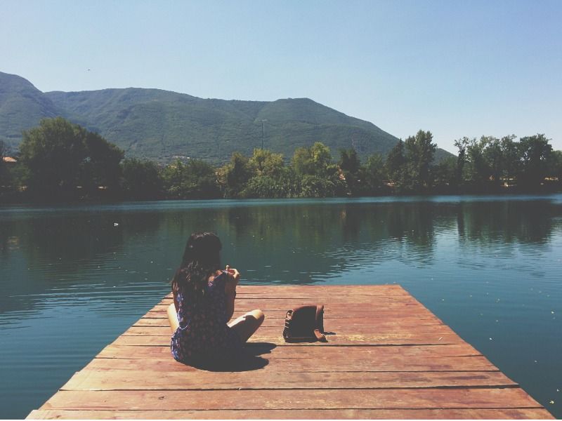 femme assise sur une corniche en bois regardant la rivière et un beau paysage - Comment créer un vlog - Image
