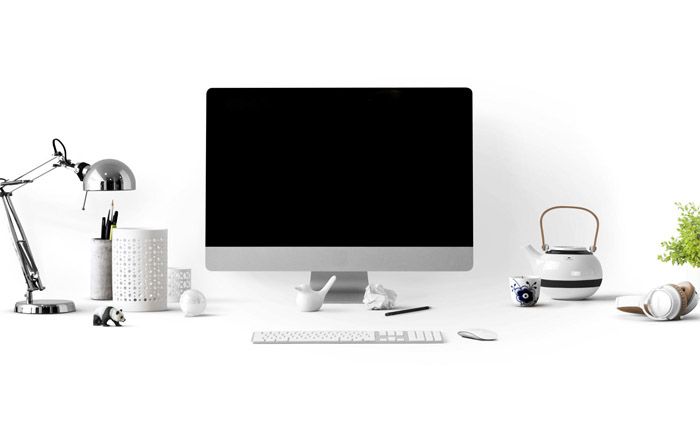 Office desk setup with iMac, desk lamp, panda figurine, headphones, kettle, cup, plant, and stationery on a white background - The ultimate guide to growing your social media following - Image