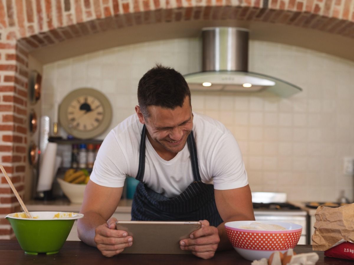 Homem em um tablet na cozinha com pratos