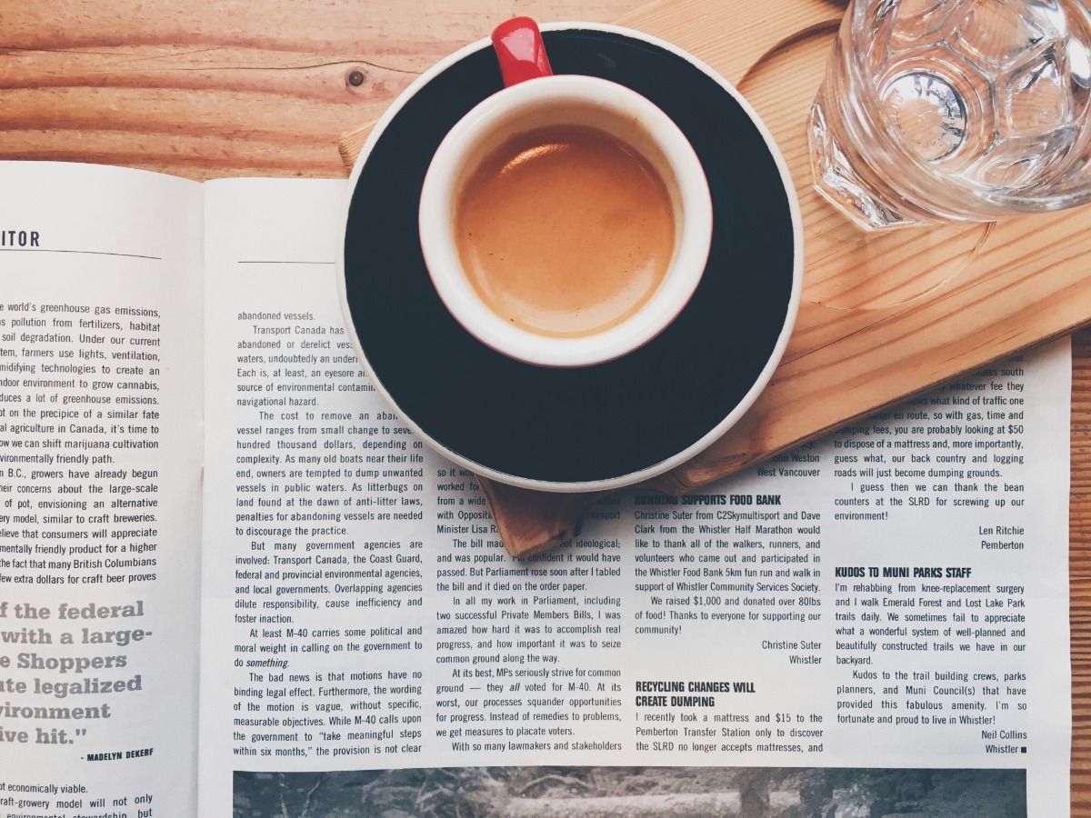 Kaffee und ein Glas Wasser auf Zeitungspapier auf dem Tisch