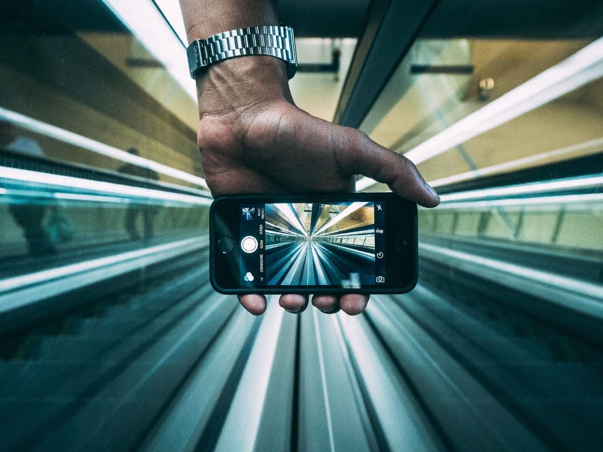 Hand hält Smartphone-Kamera, um Rolltreppe zu filmen