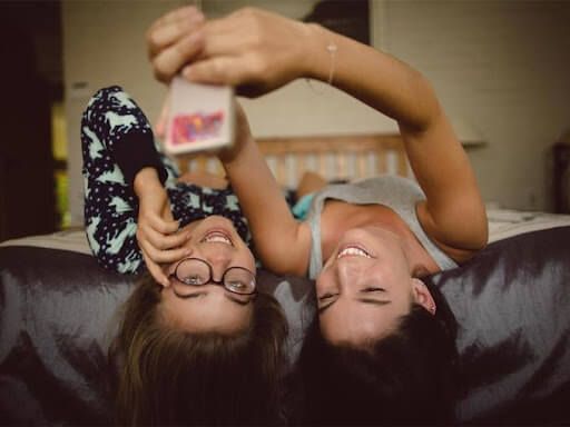 Two young girls take a selfie while lying on the bed - How to design clever student council posters, 30 ideas to boost your creativity - Image