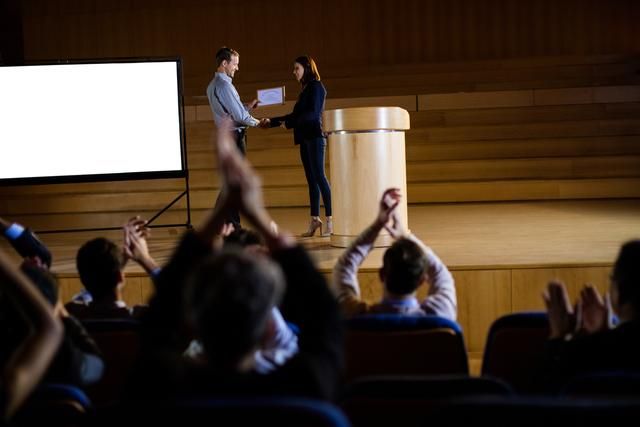 Two people shake hands on stage - The 100 best event marketing ideas - Image