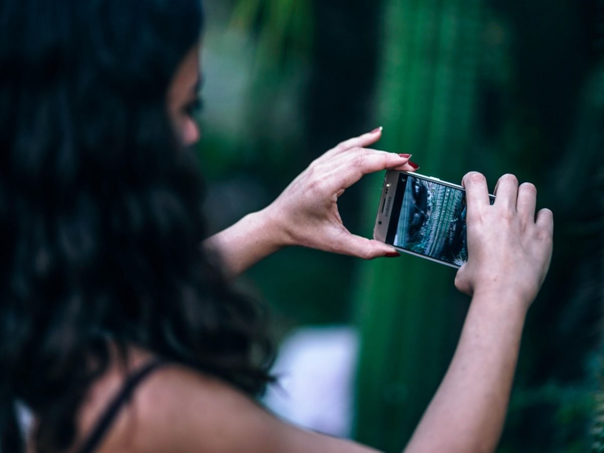 A young woman takes pictures on her smartphone - Essential video marketing tips for beginners - Image